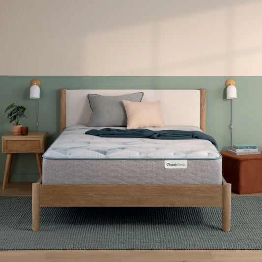 Beautysleep by Beautyrest mattress in a brown bedframe in a room setting with a lamp and nightstand.