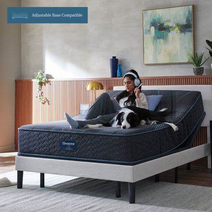 Woman sitting on Beautyrest Hybrid Plush Mattress with her dog writing on a notepad with her mattress elevated on an adjustable base.