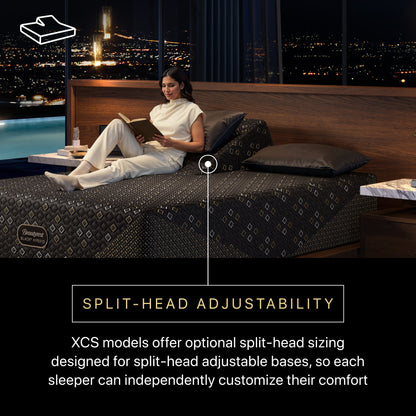 Woman reading a book on a Beautyrest Black Hybid XCS split-head mattress with an adjustable bedframe with a cityscape view.
