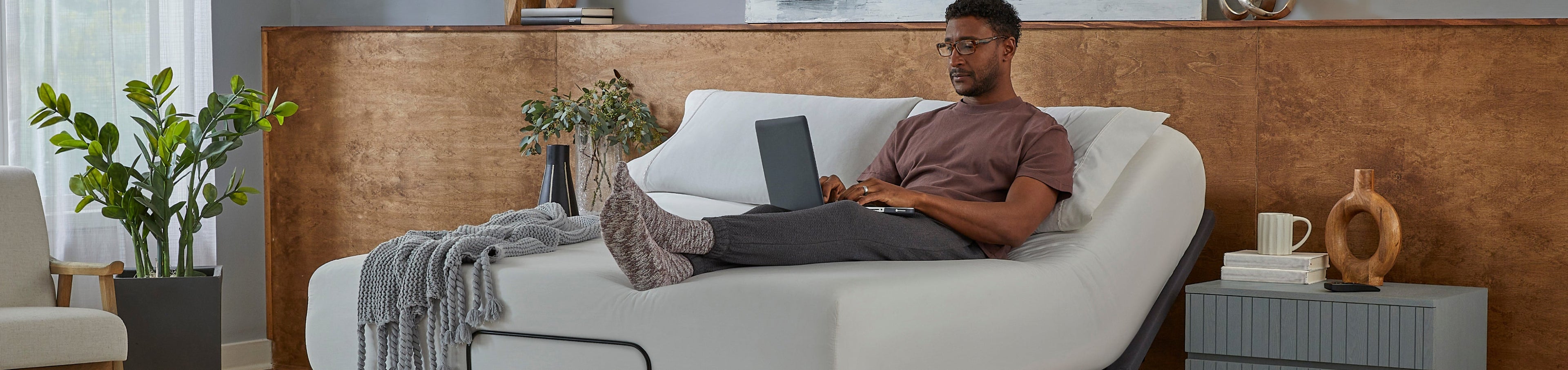 Man sitting on a white mattress slightly elevated on a baselogic adjustable base